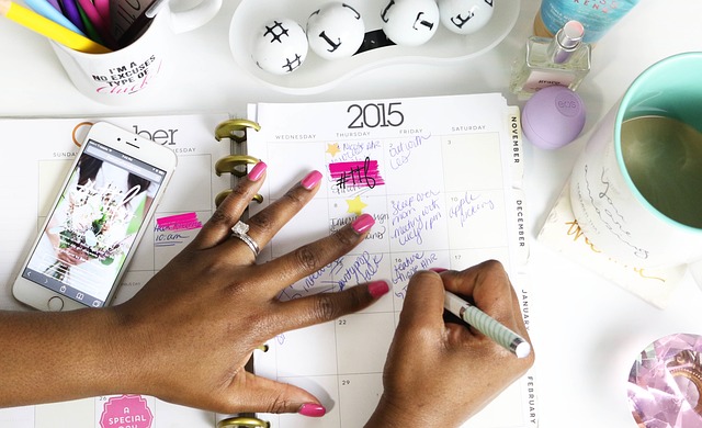 A person writing notes and planning in a paper calendar planner