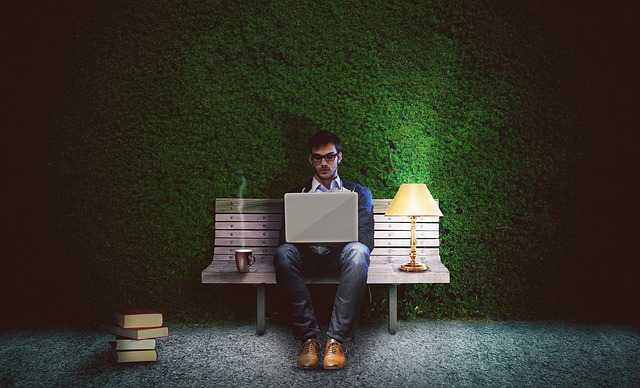 A man sitting on a bench using a laptop computer