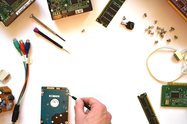 Computer hardware components, tools, and a hand repairing a hard drive
