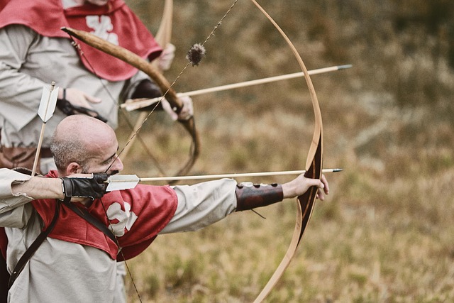 Archers in medieval clothing aiming wooden longbows