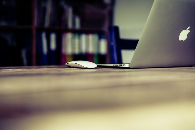 A laptop computer and a wireless mouse on a wooden desk