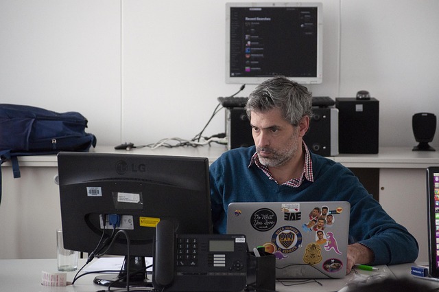 A man working at a desk with a monitor and laptop