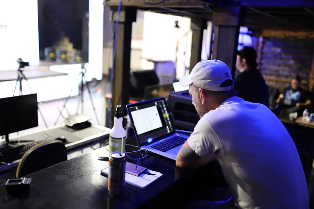 A man wearing a cap working on a laptop at a desk