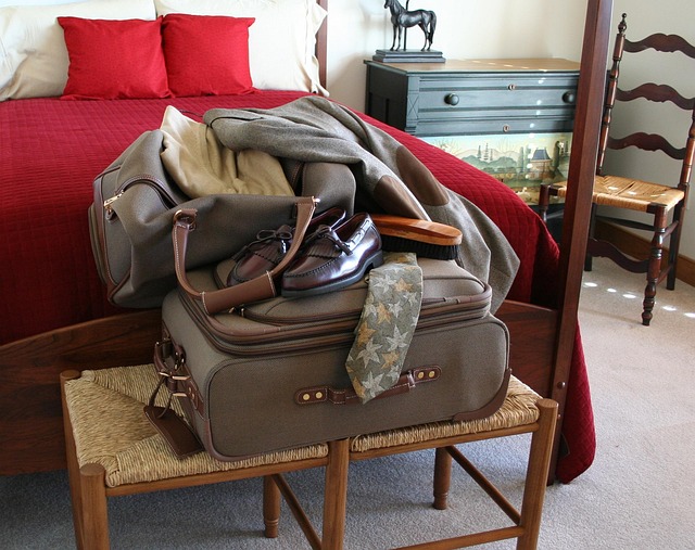 Packed luggage, shoes, and a tie on a bench in a bedroom