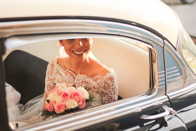 A smiling bride holding a bouquet inside a classic car