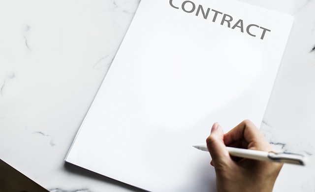 A hand holding a pen over a contract document