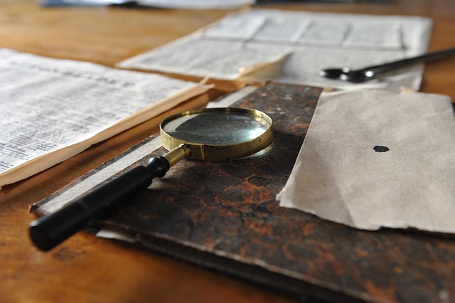 A brass magnifying glass resting on old documents on a desk