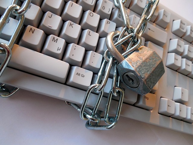 A computer keyboard wrapped in metal chains with a padlock