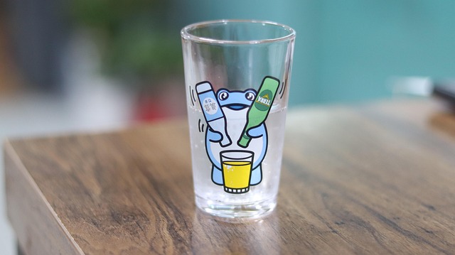 A clear drinking glass with a cartoon frog printed on it