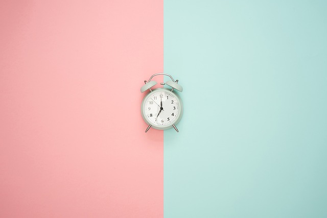 An alarm clock centered between pink and light blue backgrounds