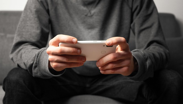 A person holding a smartphone horizontally while playing a game