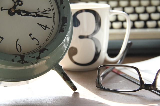 A vintage analog clock next to glasses and a coffee mug