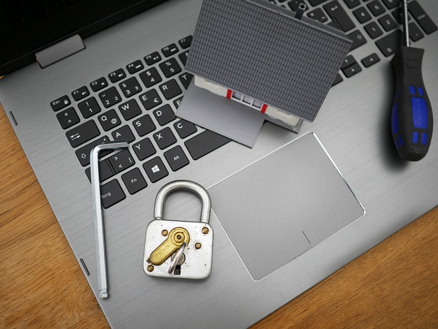 A padlock, tools, and miniature house on a laptop keyboard
