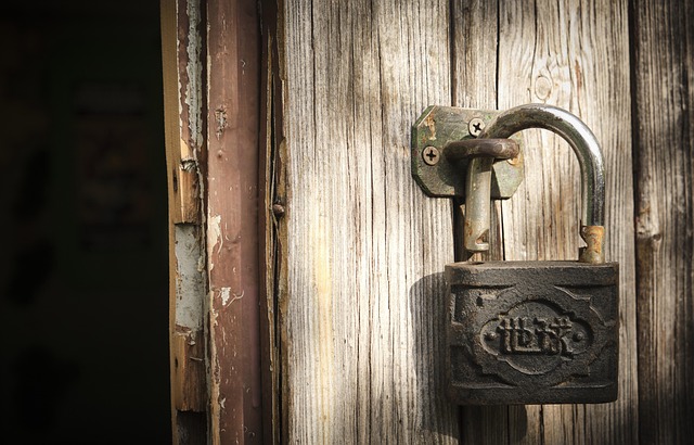 An unlocked padlock on a wooden door