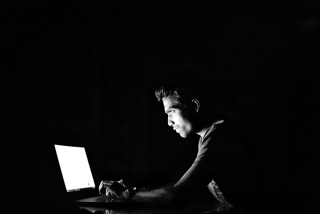 A person using a laptop in a dark room