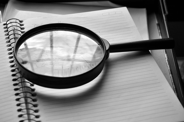 A magnifying glass resting on an open spiral notebook