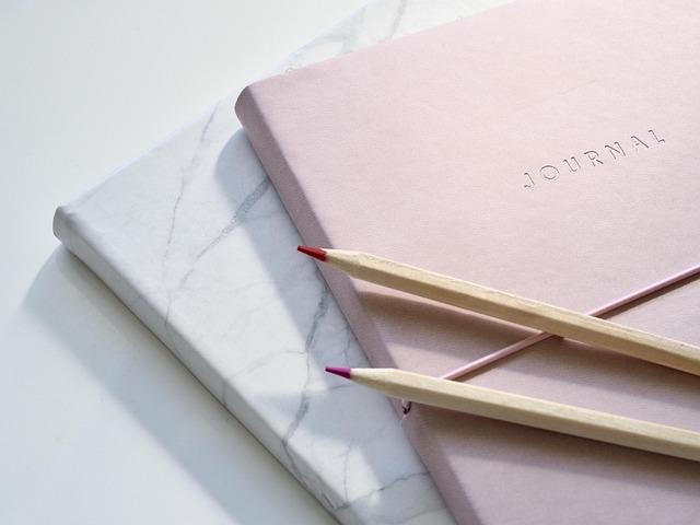 A pink journal and two pencils on a marble notebook