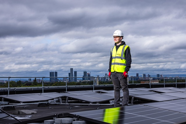 A worker in safety gear standing on a rooftop with solar panels