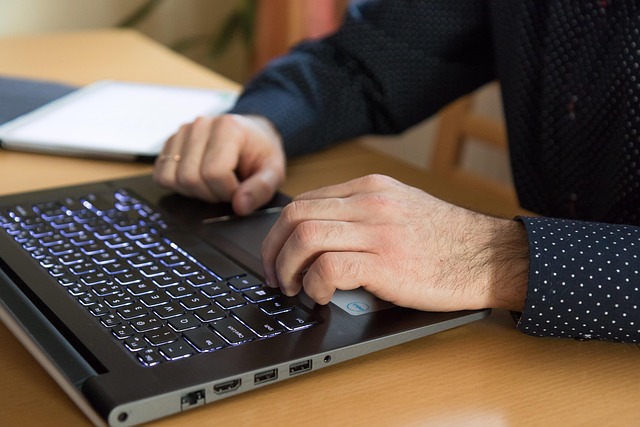 A person typing on a laptop computer at a desk