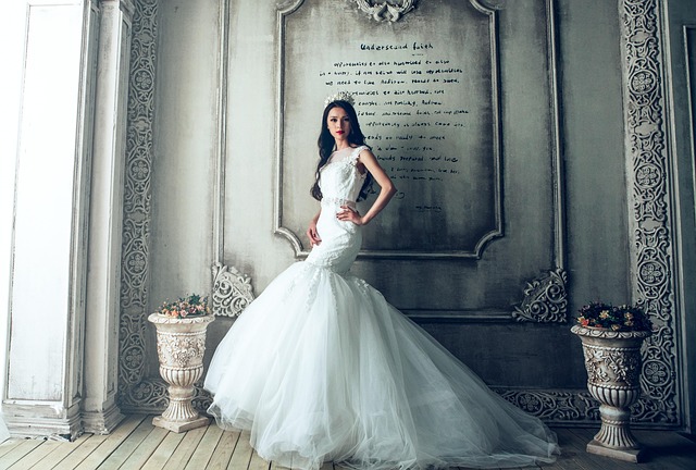 A bride in an elaborate wedding dress posing in a room