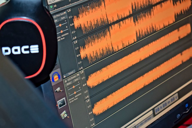 Audio editing software with waveforms on a monitor screen and headphones