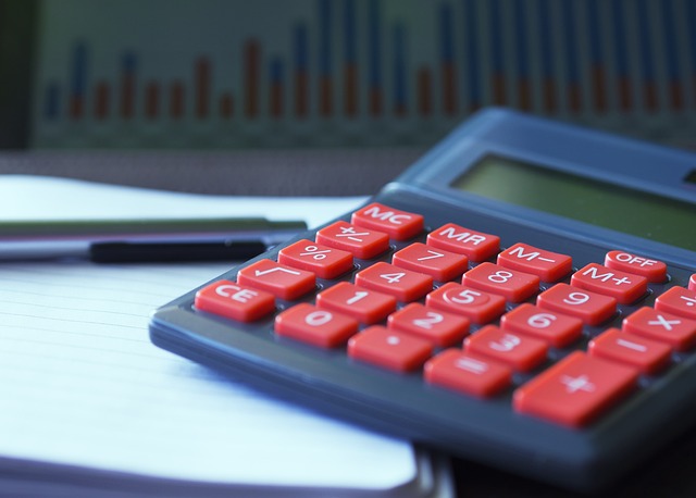 A calculator with red buttons resting on paper