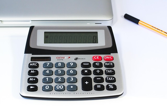 A calculator sitting on a desk next to a laptop