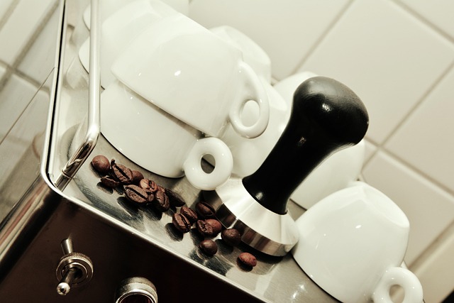 Coffee cups, coffee beans, and a tamper on an espresso machine