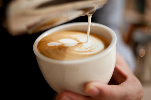 Steamed milk being poured into a cup to create latte art