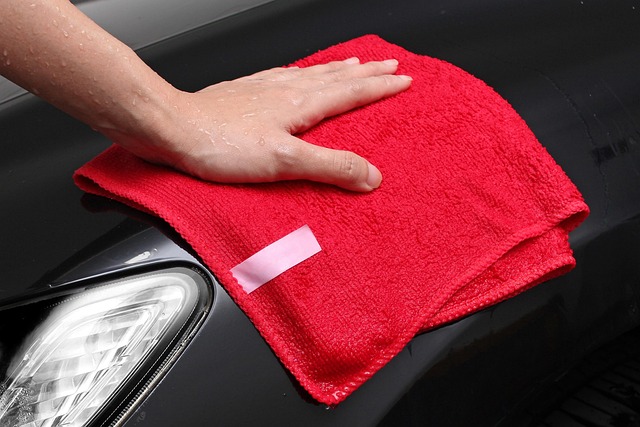Hand wiping a computer monitor screen with a microfiber cloth