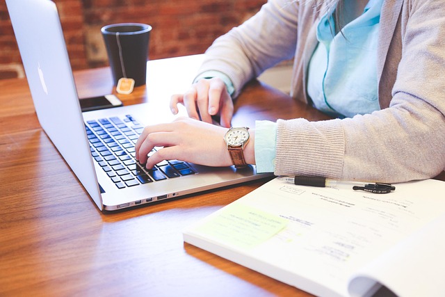 A person typing on a laptop at a desk