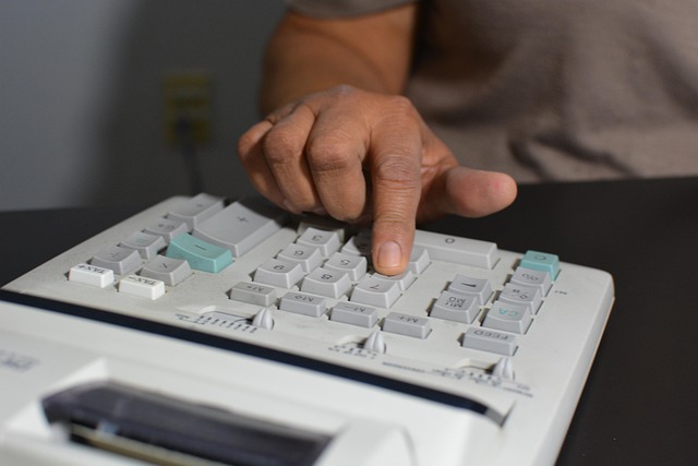 A person's hand using an adding machine calculator
