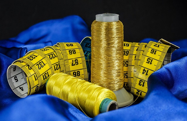 Yellow measuring tape and thread spools on blue fabric